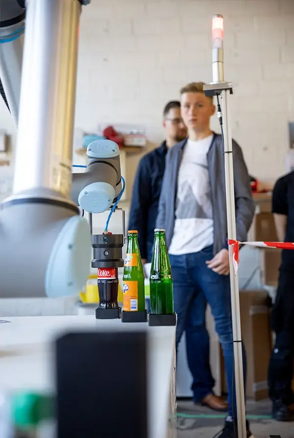 Cobot von Universal Robots greift Cola-Flasche zum Öffnen